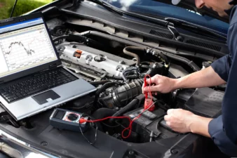 Elektros autoservisas, autoelektrikas tikrina masina.
